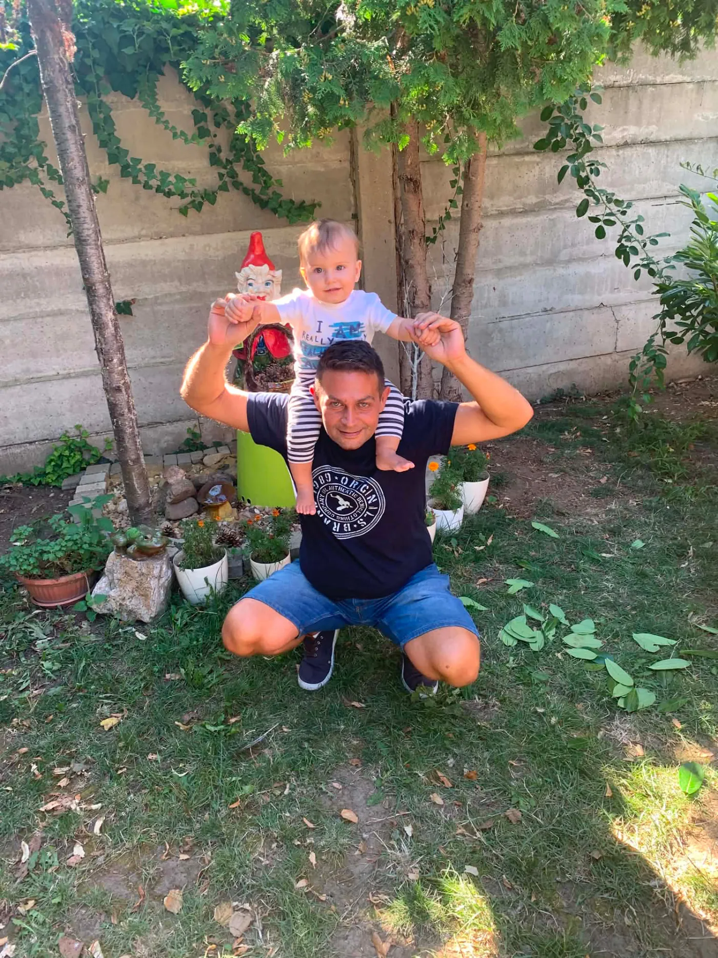 Dieťa na pleciach dospelého v záhrade medzi kvetmi